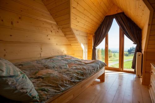 OrawkaDomek Nad Doliną的木制客房的一张床铺,设有大窗户