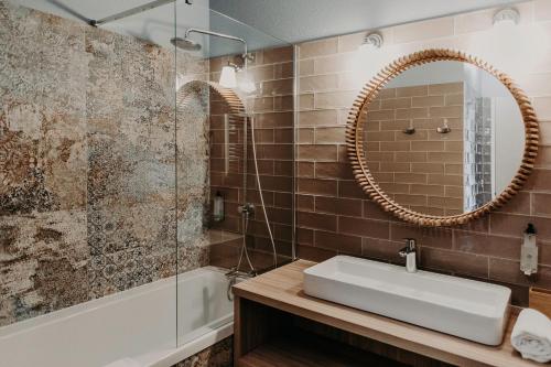卡布勒通Baya Hotel的浴室配有盥洗盆、镜子和浴缸