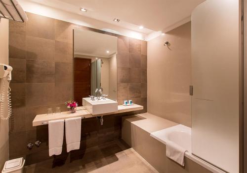 罗萨里奥索兰斯总统酒店的一间带水槽、浴缸和镜子的浴室