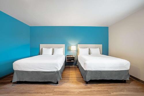 那不勒斯WoodSpring Suites Naples的蓝色墙壁客房的两张床