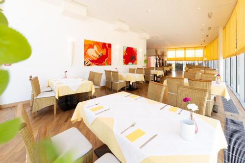 格莱斯多夫Business Hotel Ambio Gleisdorf的餐厅配有白色的桌椅和墙上的绘画作品