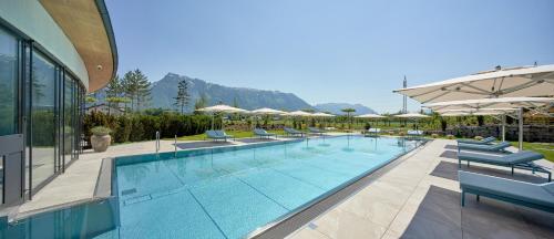 瓦兹Laschenskyhof Hotel & Spa的一个带椅子和遮阳伞的大型游泳池