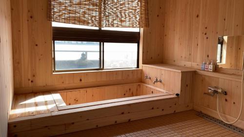 唐津唐津城堡河畔日式旅馆的木制浴室设有浴缸和窗户。