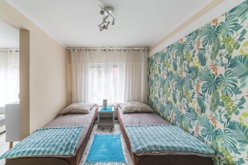 亚斯塔尔尼亚Wera Domki的客房设有两张床和一堵带热带壁纸的墙