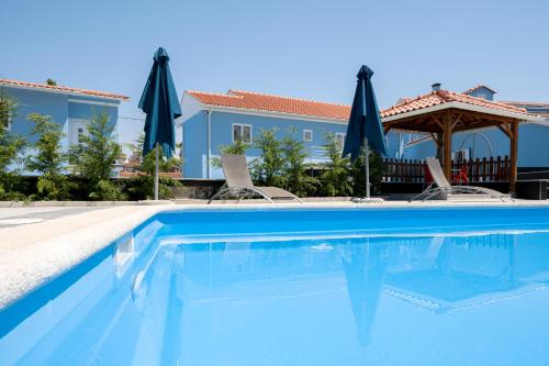 CojaVilla Montês Guesthouse的一个带椅子和遮阳伞的蓝色游泳池