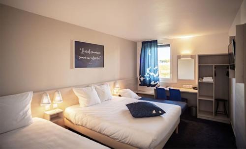 普罗旺斯地区萨隆Ace Hôtel Salon de Provence的酒店客房设有两张床和窗户。