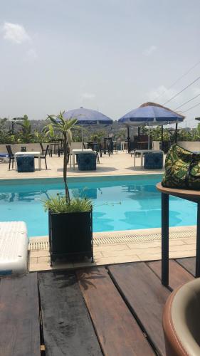 弗里敦The Swiss Hotel Freetown的木甲板上种有盆栽植物的游泳池