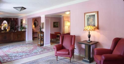 芬奇蒙娜丽莎酒店的客厅配有2把红色椅子和桌子