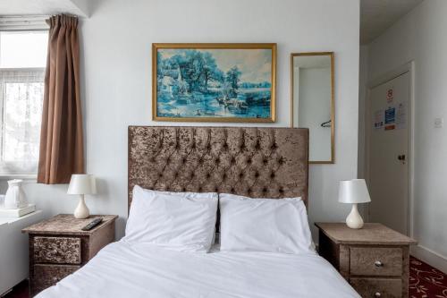 哈罗Euro Hotel Harrow的一间卧室配有一张带白色床单和绘画的床。