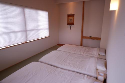 石垣岛Guest House Ishigaki的配有窗户和时钟的客房内的两张床