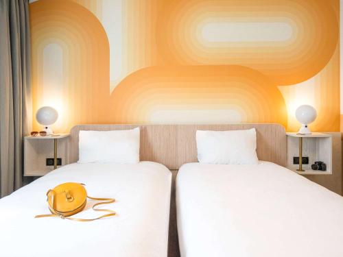 佩尔蒂ibis Styles Pertuis Portes du Luberon的两张床,配有白色床单和黄色帽子