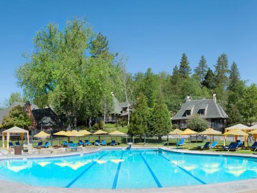 箭头湖UCLA Lake Arrowhead Lodge的度假村内的大型游泳池,配有椅子和遮阳伞