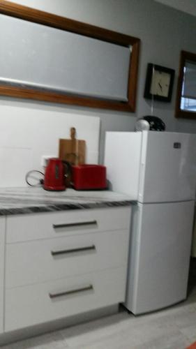 凯阿玛Never Inn的厨房配有白色冰箱和红色用具