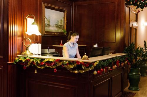 考波什堡Hotel Dorottya的一位女士坐在一张桌子上,拿着麦克风