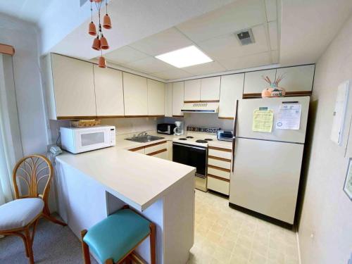 大洋城Ocean Princess 207的厨房配有白色冰箱和带椅子的柜台