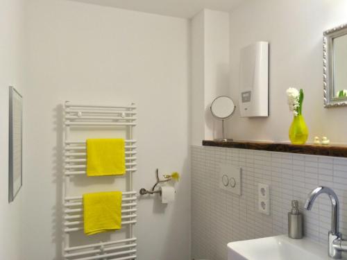 科隆aTa & oMo的浴室位于水槽旁的架子上,配有黄色毛巾
