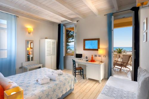 卡利亚里Hotel La Villa Del Mare的一间卧室设有一张床和一张书桌,享有海景