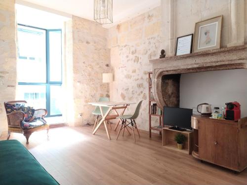 波尔多B&B Bordeaux Saint Michel的客厅配有电视和桌椅