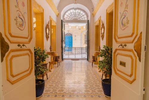 瓦莱塔Casa Rocca Piccola B&B的建筑中带有黄色墙壁和盆栽的走廊