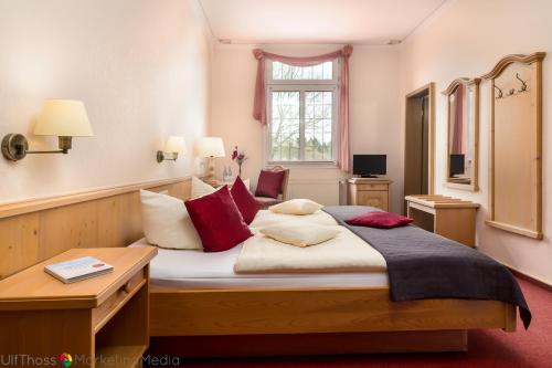 古梅尔斯巴赫莱因霍尔德酒店的一间卧室配有一张带红色枕头的大床