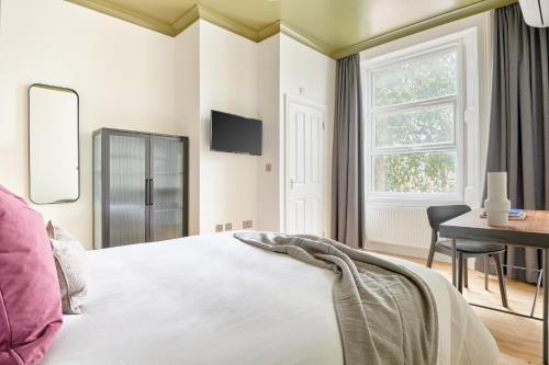 伦敦Sonder Camden Road的一间卧室配有一张床、一张书桌和一个窗户。
