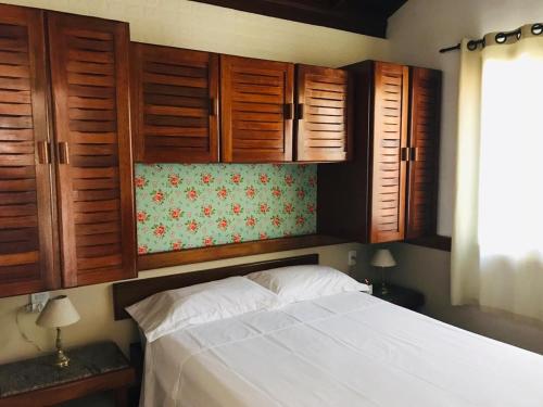 弗洛里亚诺波利斯Casa Chale 10 Florianópolis的一间卧室配有木制橱柜和一张白色的床。
