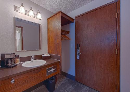 凯洛格Silver Inn的一间带水槽和镜子的浴室以及一扇木门