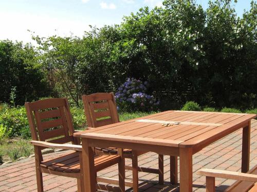 Trans4 person holiday home in Lemvig的砖砌庭院里的一张木桌和两把椅子