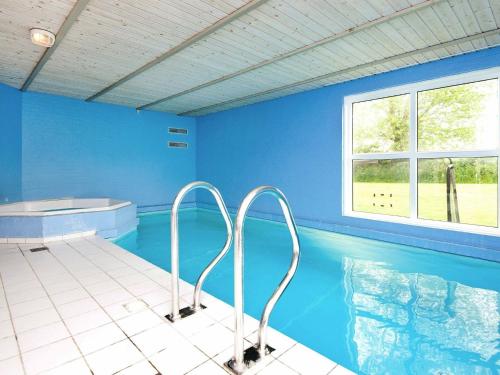 诺德堡12 person holiday home in Nordborg的一个带蓝色墙壁和窗户的游泳池