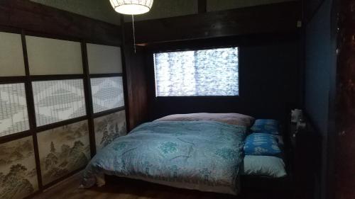 大岛築100年の宿【はぶの家】的一间带床的卧室,位于带窗户的房间内