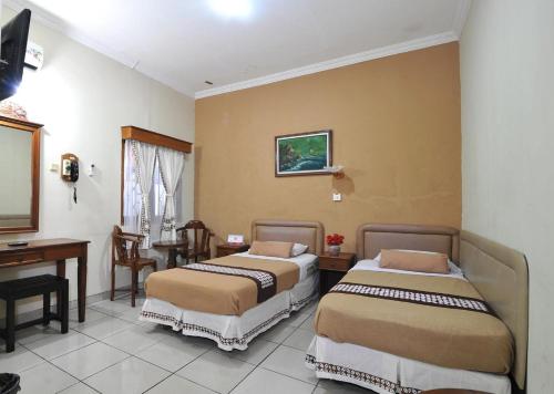 日惹Hotel Mataram Malioboro的酒店客房配有两张床和一张书桌