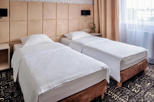 拉辛Falenty Biznes i Wypoczynek的酒店客房设有两张床和窗户。