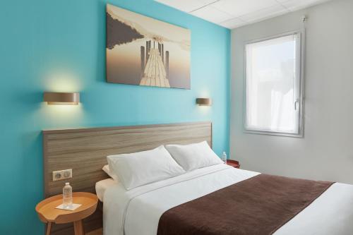 RuaudinAshley Hotel Le Mans Sud的一间卧室设有一张床和蓝色的墙壁