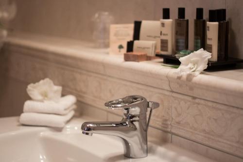 乌赫尔堡施朗斯酒店的浴室水槽、水龙头和架子上的毛巾