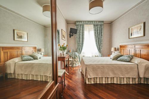 佛罗伦萨乐坎德拉邱比酒店的酒店客房,设有两张床和镜子