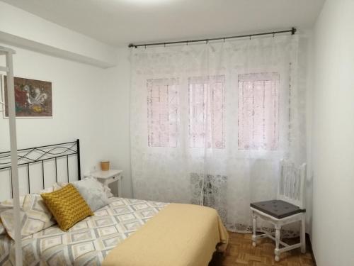 希洪Apartamento Quety Gijón的卧室配有床、椅子和窗户。