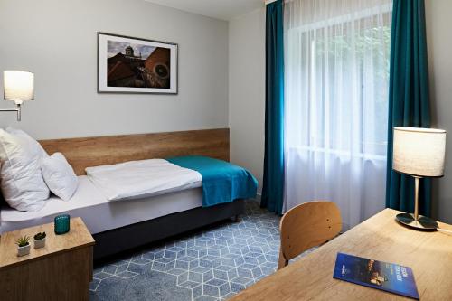 艾斯特根Hotel Adalbert Szent Tamás ház的酒店客房配有一张床铺和一张桌子。