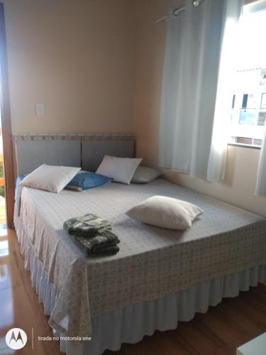 瓦尔任阿Suítes da Rô - hospedaria familiar diária e temporada的一间卧室配有一张带两个枕头的床