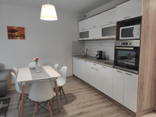 德布勒森Hatvan Corner Apartments的厨房配有白色橱柜和桌椅