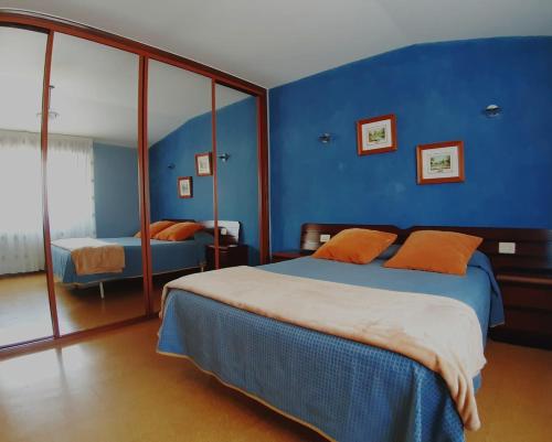 尼格兰El Retiro的一间卧室拥有蓝色的墙壁,配有一张带橙色枕头的床。