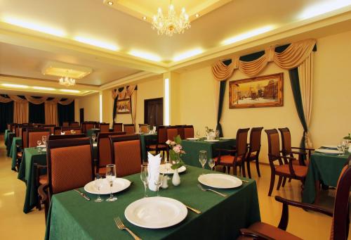 沃罗涅什沃罗涅日酒店的餐厅设有绿色桌椅和吊灯。
