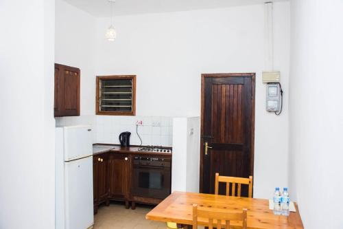 达累斯萨拉姆Baobab Village One Bedroom apartment - Type I的厨房配有木桌和木门。