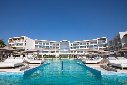 帕福斯Atlantica Mare Village Paphos的酒店设有带躺椅和遮阳伞的游泳池