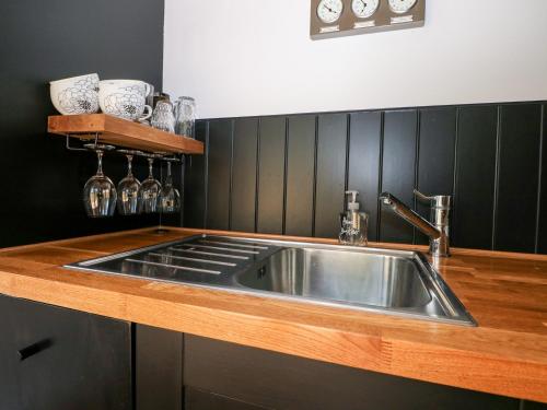 特灵Kub House的厨房设有不锈钢水槽和黑色墙壁