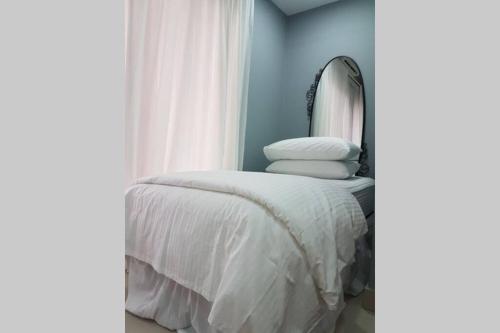 莎阿南Private studio at Bukit Jelutong的一间带镜子的卧室和一张铺有白色床单的床