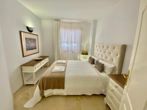 塞维利亚Portico Sevilla的白色卧室配有一张大床和一张书桌