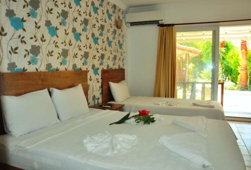 厄吕代尼兹Durak Hotel ölüdeniz的酒店客房,配有两张带鲜花的床
