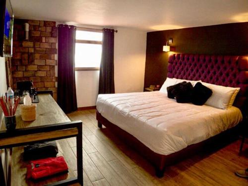 米内拉尔德尔蒙特Hotel Santiurde SOLO ADULTOS的一间卧室配有一张大床和红色床头板