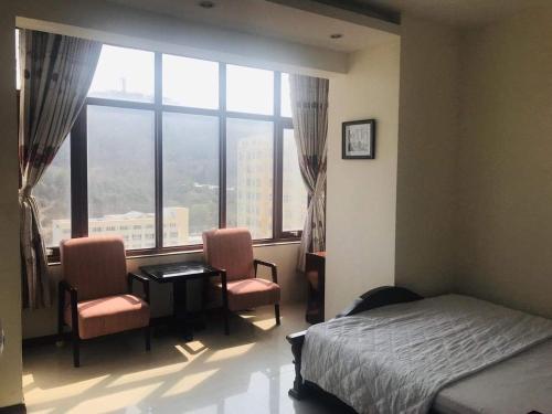 头顿Căn hộ Sơn Thịnh - Homestay的一间卧室配有一张床、两把椅子和一个窗户