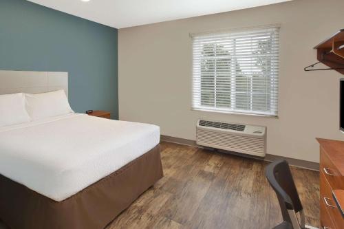圣查尔斯WoodSpring Suites St Louis St Charles的一间卧室配有一张床、一个窗口和一张书桌